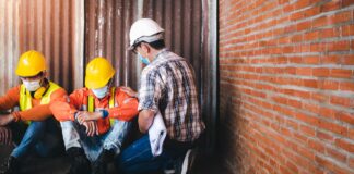 Supervisors and construction workers sit sad at the job site.