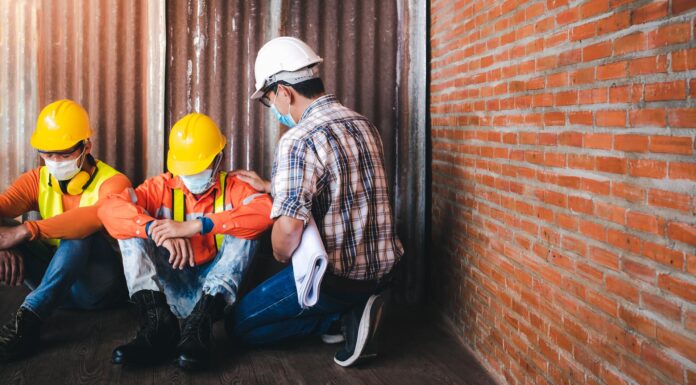Supervisors and construction workers sit sad at the job site.