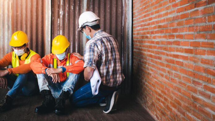 Supervisors and construction workers sit sad at the job site.